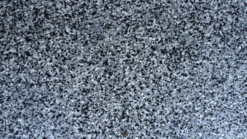 Close-up of a full-broadcast vinyl flake epoxy floor in gray, black, and white blend