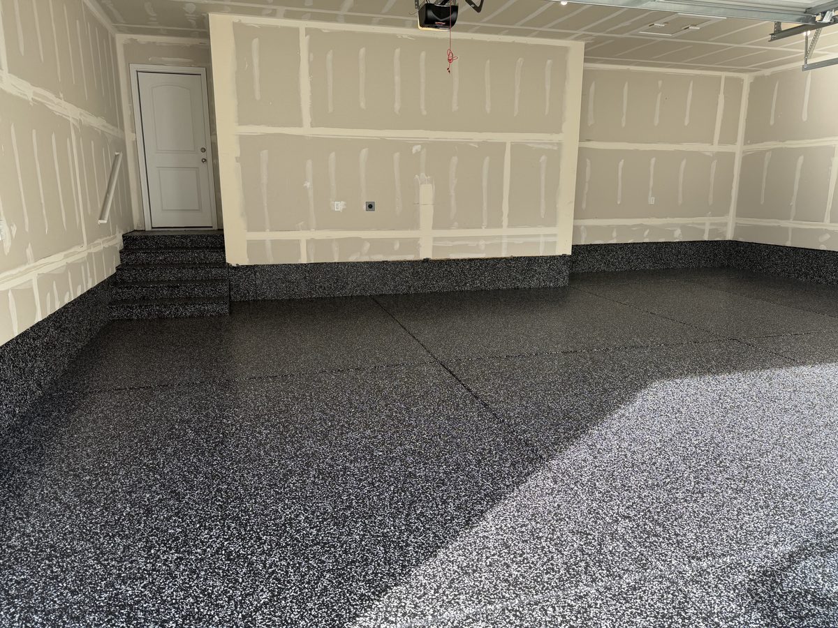 Finished garage with a black-and-white full-flake epoxy floor and a coved flake base up the walls
